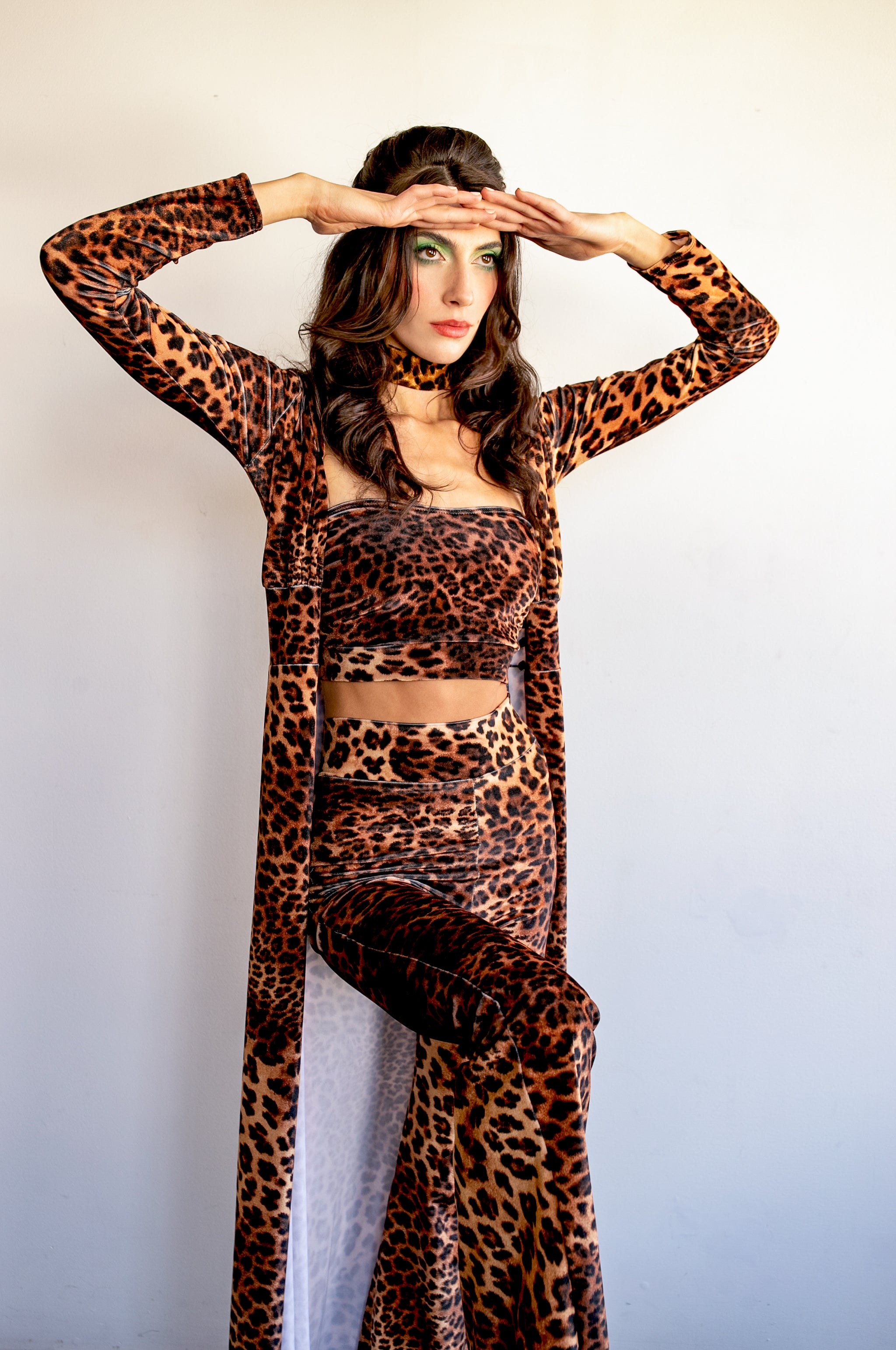 A person wearing a matching set of leopard print hooded robe, tube top, and flare pants, striking a pose with hands raised against a plain background.