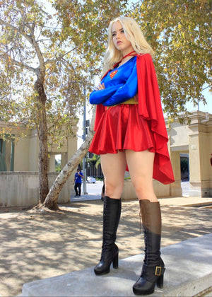 Person in a superhero costume standing outdoors with trees and buildings in the background